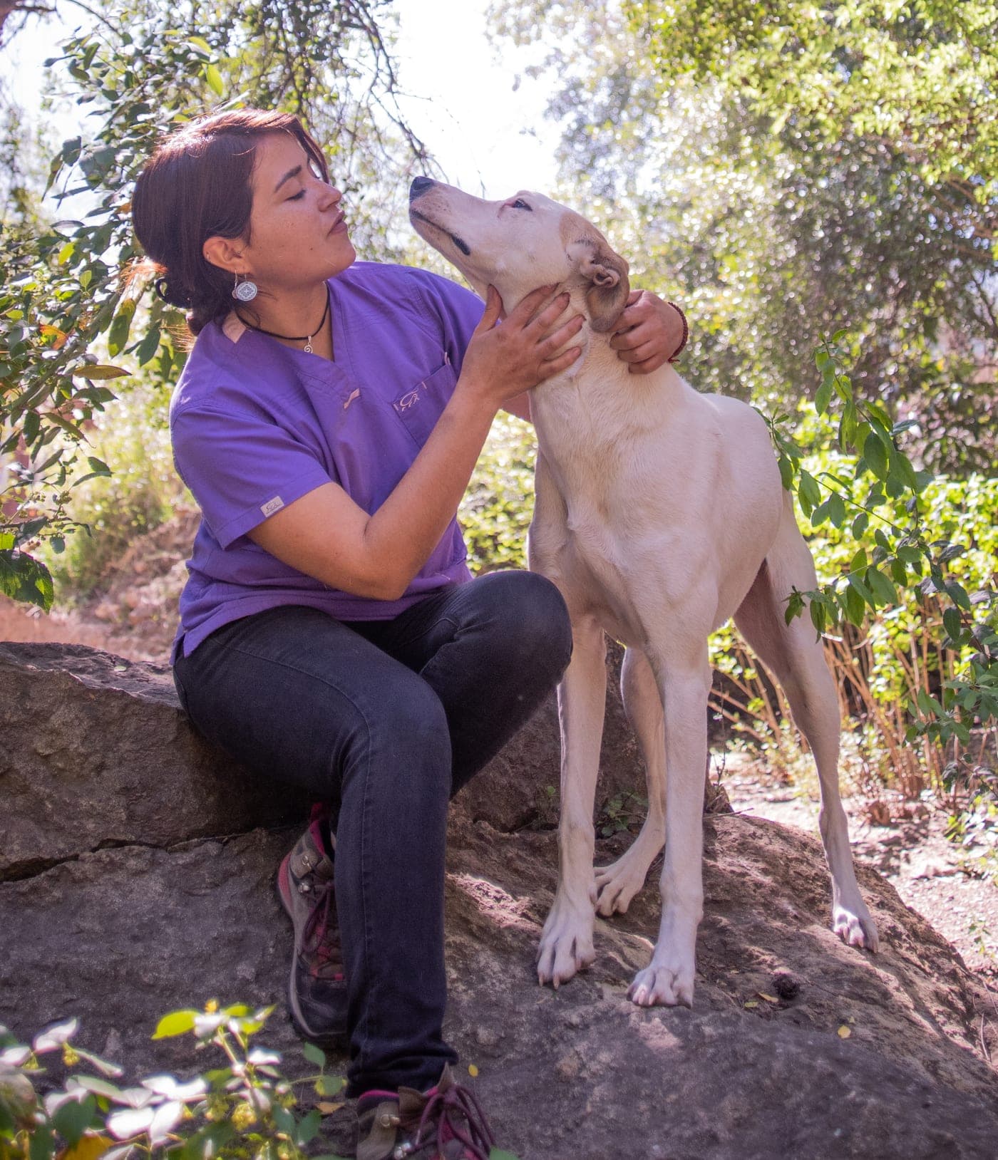 Michelle Madaune, médico veterinario, sostiene con las dos manos la cara de un perro de pelaje claro que la mira de cerca.